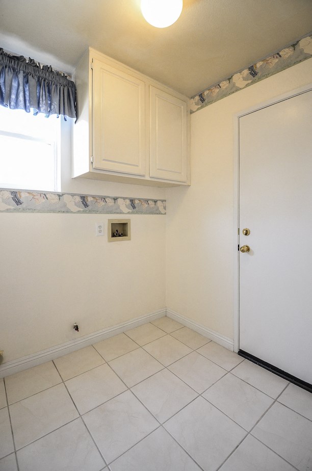 a small room with a white tile floor and white cabinets