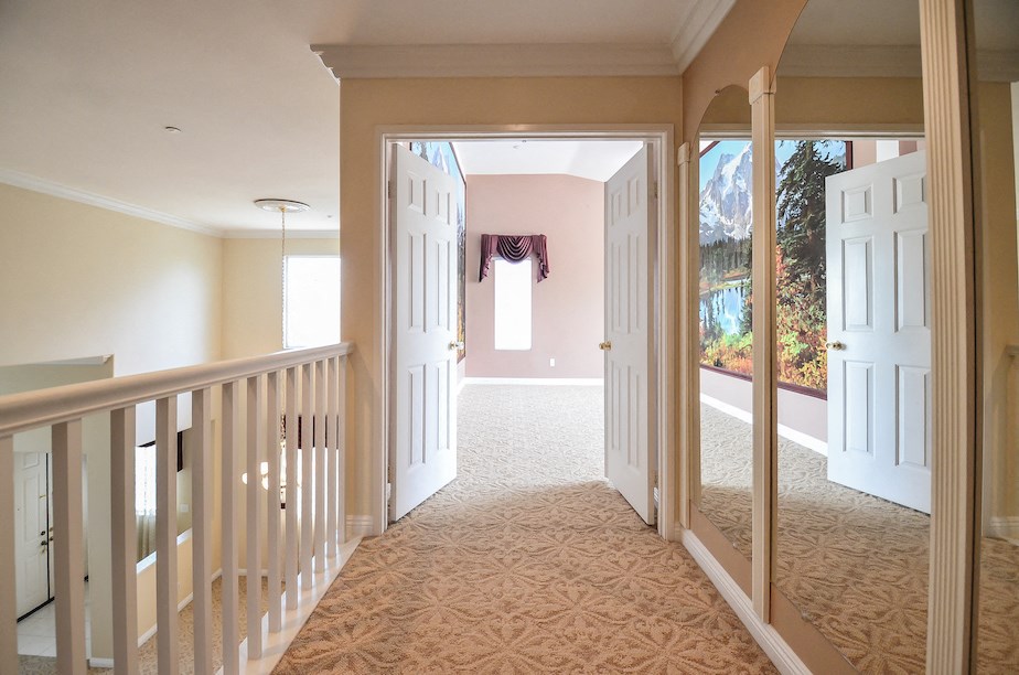 a staircase with a view of a living room and a hallway with a door open