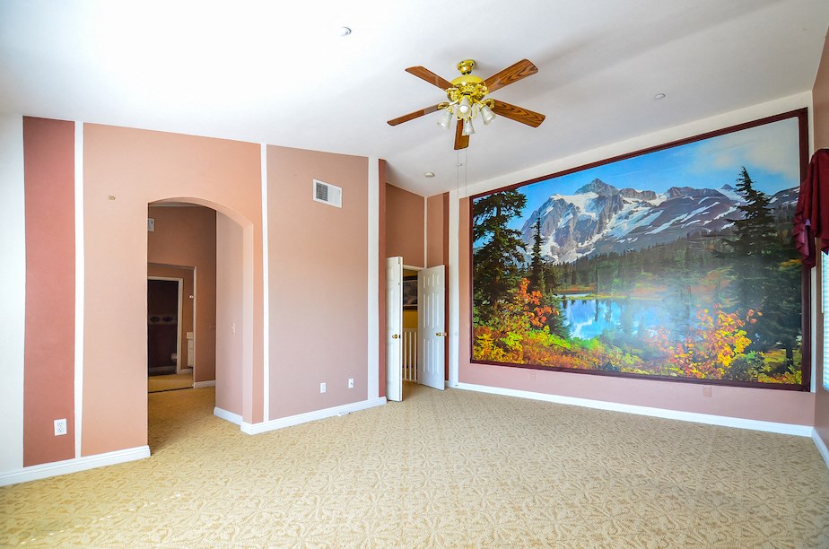 a room with a large painting on the wall and a ceiling fan