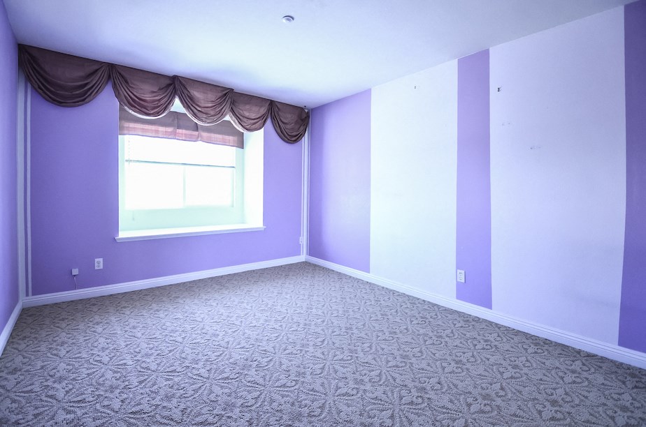 an empty room with purple walls and a window