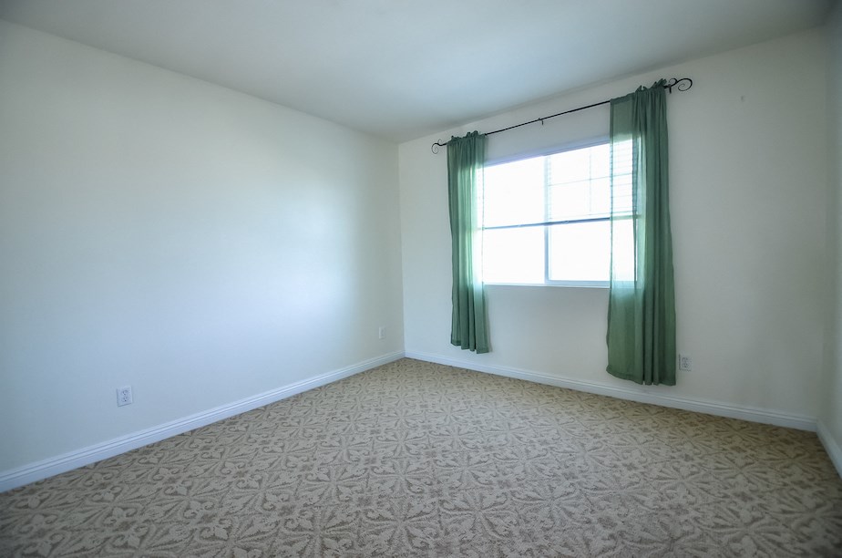 an empty room with a window and a green curtain
