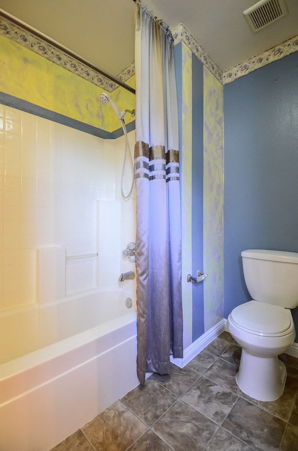 a bathroom with a toilet and a tub and a shower curtain