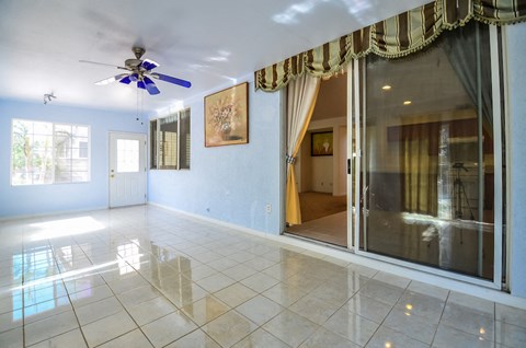the living room of a house with a large window and a ceiling fan
