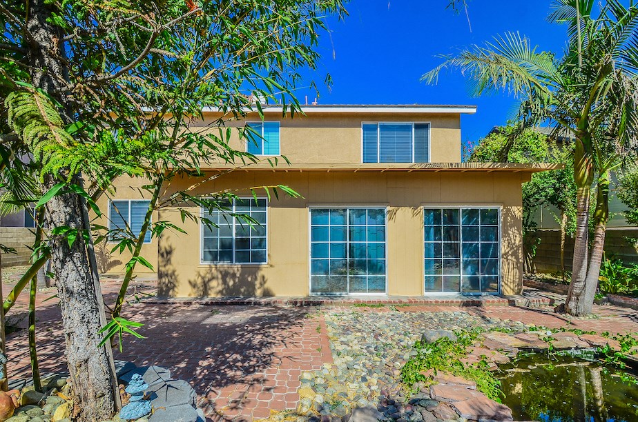 a yellow house with trees and a pond in front of it