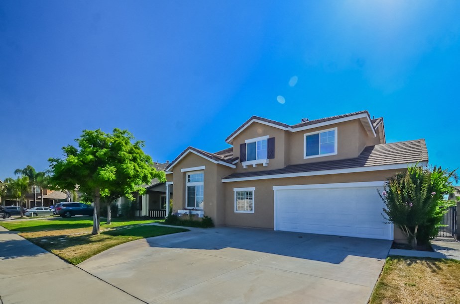 a beige house with a white garage door and a tree