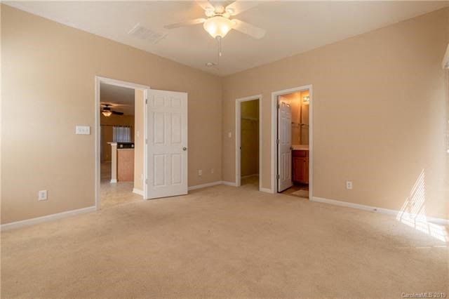 A room with a ceiling fan and carpeted floor.