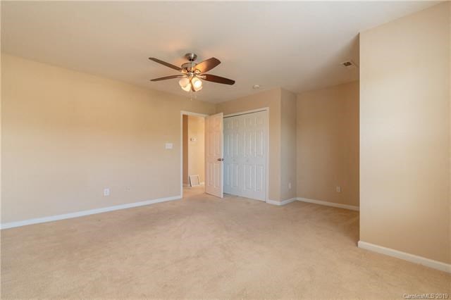 A room with a ceiling fan and carpeted floor.