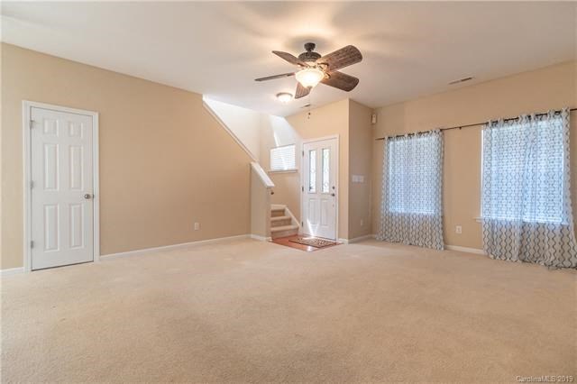 A spacious room with a staircase and a ceiling fan.