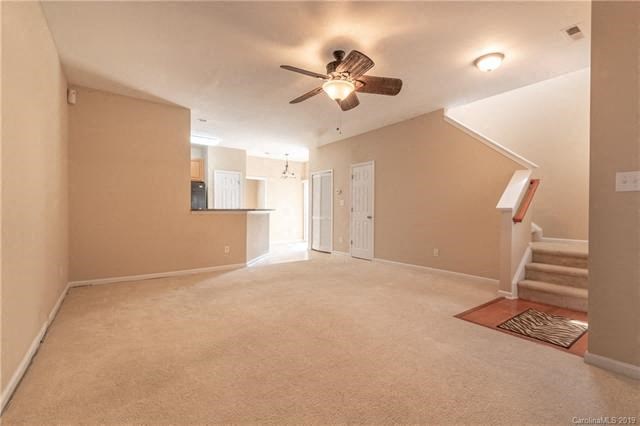 A room with a ceiling fan and carpeted floor.