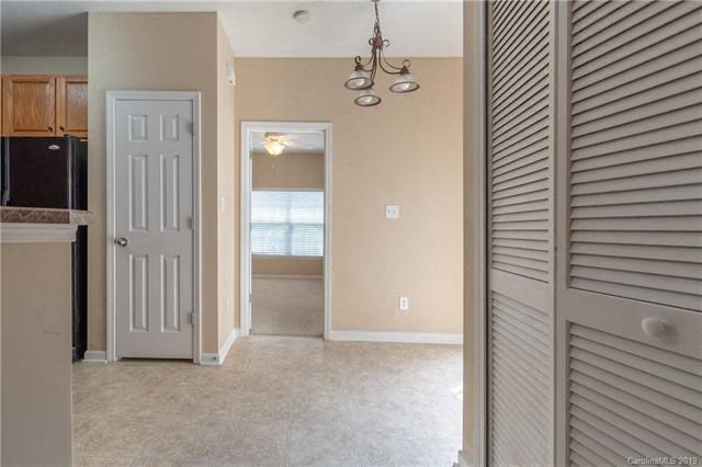 A kitchen area with a refrigerator, cabinets, and a door leading to another room.
