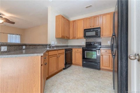 A kitchen with wooden cabinets and black appliances.