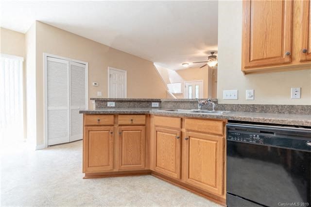 A kitchen with wooden cabinets and a black dishwasher.
