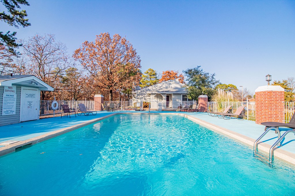 a swimming pool with a house and trees in the background