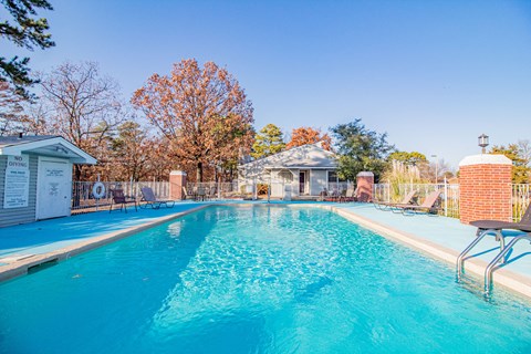 a swimming pool with a house and trees in the background
