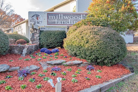 a front yard with mulch and rocks and a sign for millwood landings
