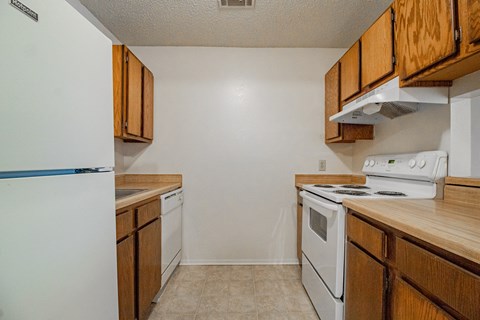 an empty kitchen with white appliances and wooden cabinets