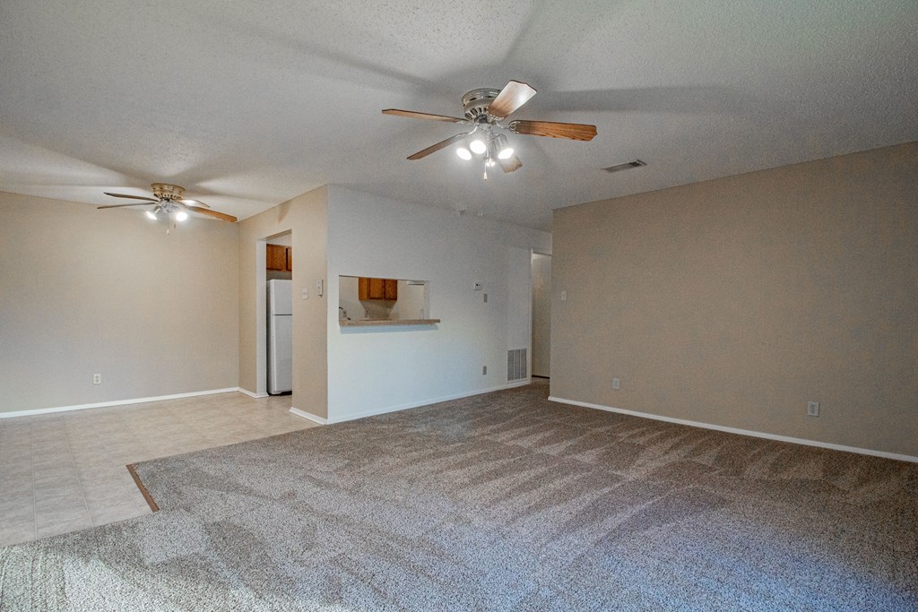 an empty living room with a ceiling fan and a rug