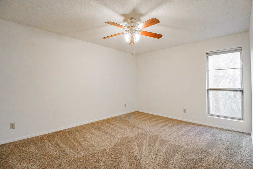 an empty room with a ceiling fan and a window