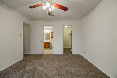 an empty living room with carpet and a ceiling fan