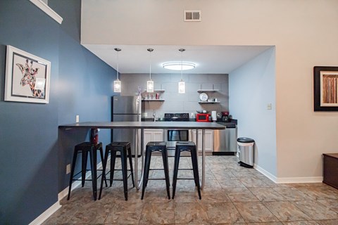a kitchen with a bar and stools and a stainless steel refrigerator