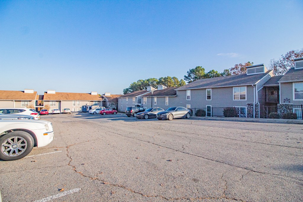 a parking lot with cars parked in front of apartment buildings