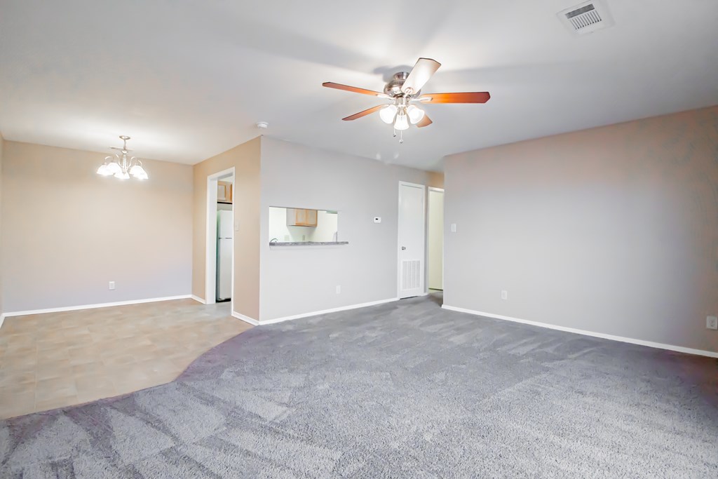 a empty living room with a ceiling fan and a carpet