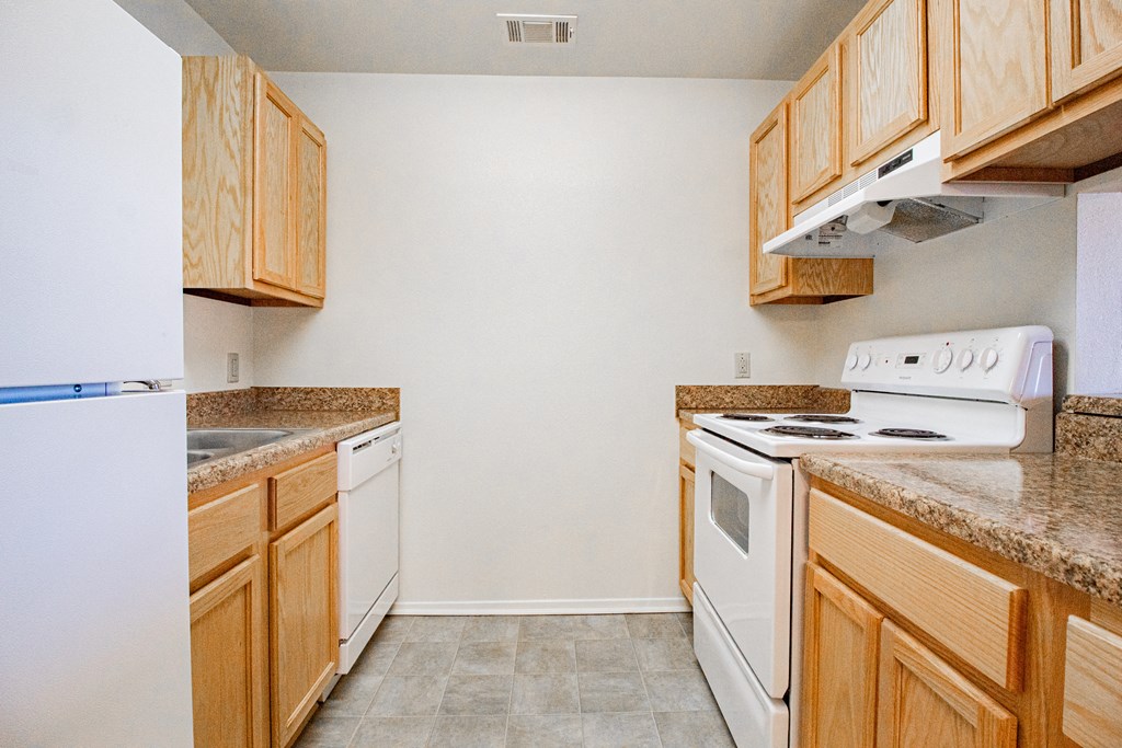 an empty kitchen with wood cabinets and white appliances