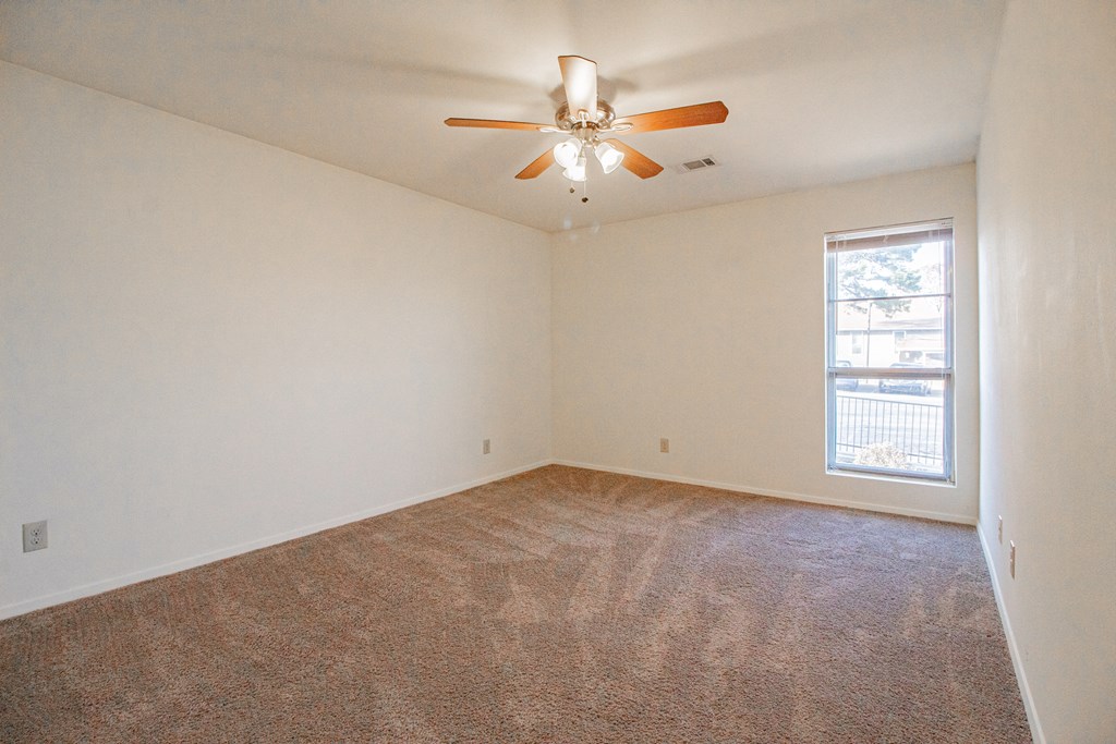 an empty living room with a ceiling fan and a window