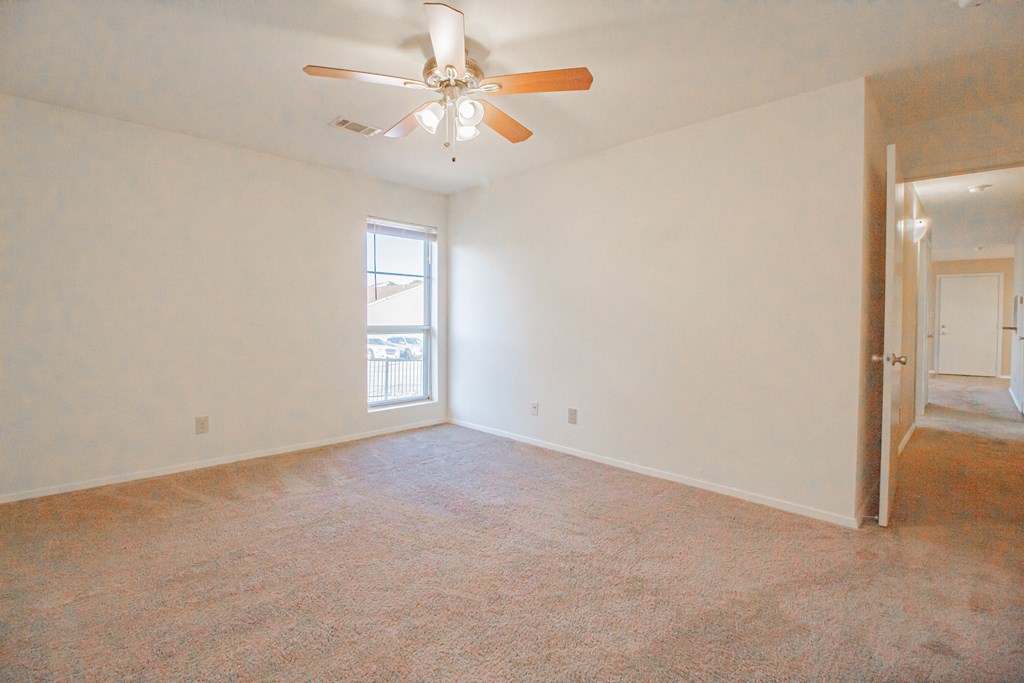 an empty living room with a ceiling fan and a window