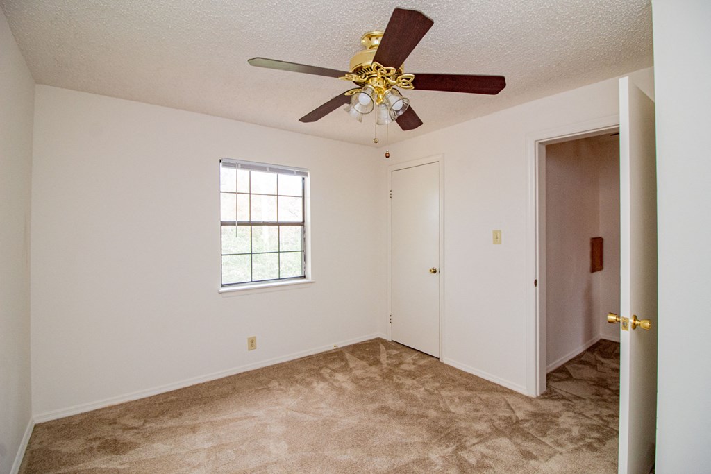 an empty living room with a ceiling fan and a door