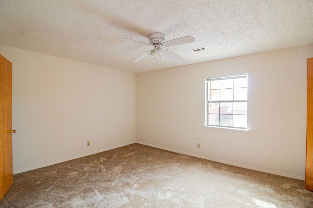 an empty room with a ceiling fan and a window