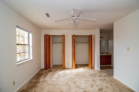an empty living room with a ceiling fan and a closet