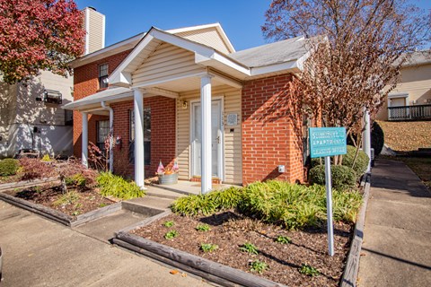 a small brick house with a blue sign in front of it