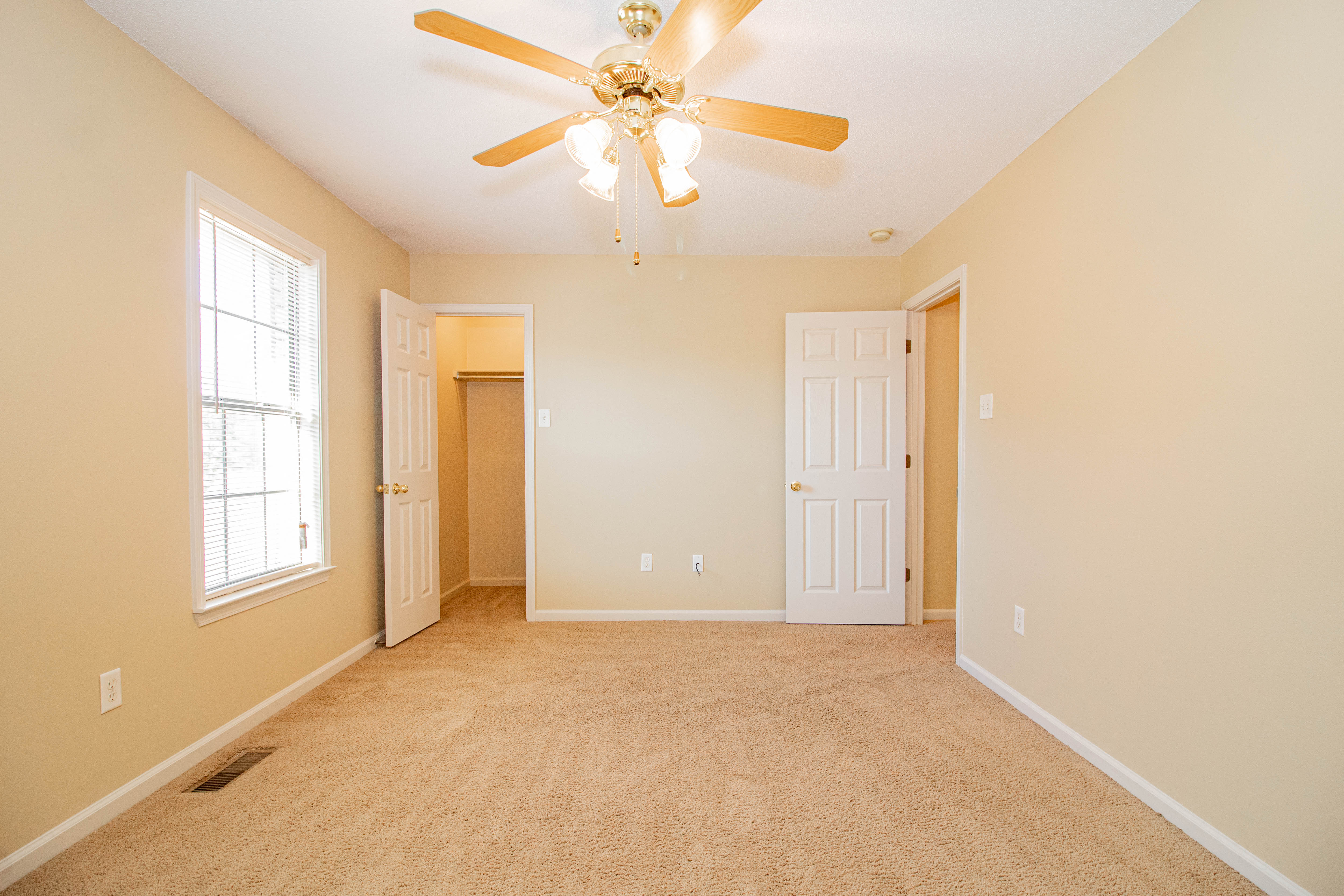 an empty living room with a ceiling fan