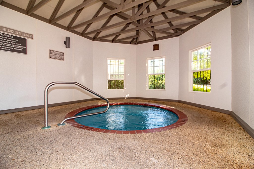 a jacuzzi in a spa room with a pool and a hand rail