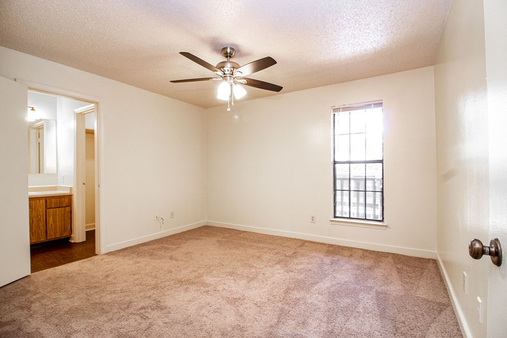 an empty living room with a ceiling fan and a window