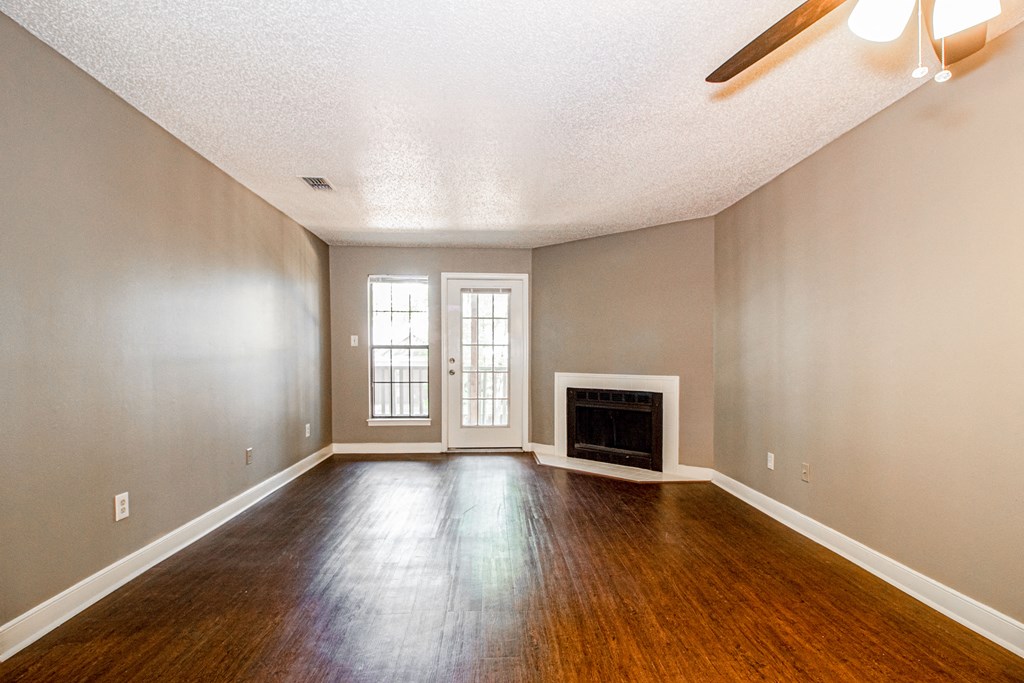 an empty living room with wood floors and a fireplace