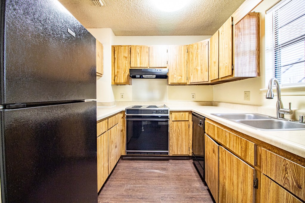a kitchen with wooden cabinets and a black refrigerator