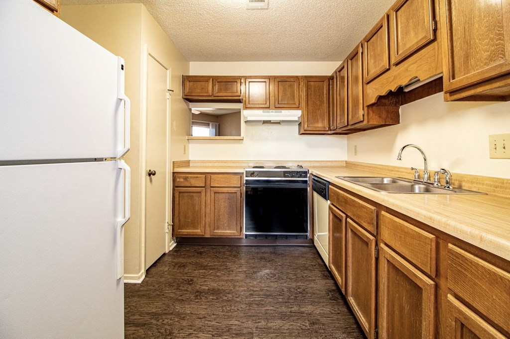 a kitchen with wooden cabinets and a refrigerator and a sink