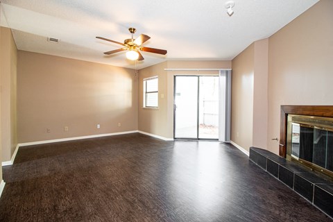 an empty living room with a fireplace and a ceiling fan