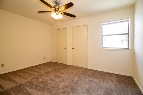 an empty living room with carpet and a ceiling fan
