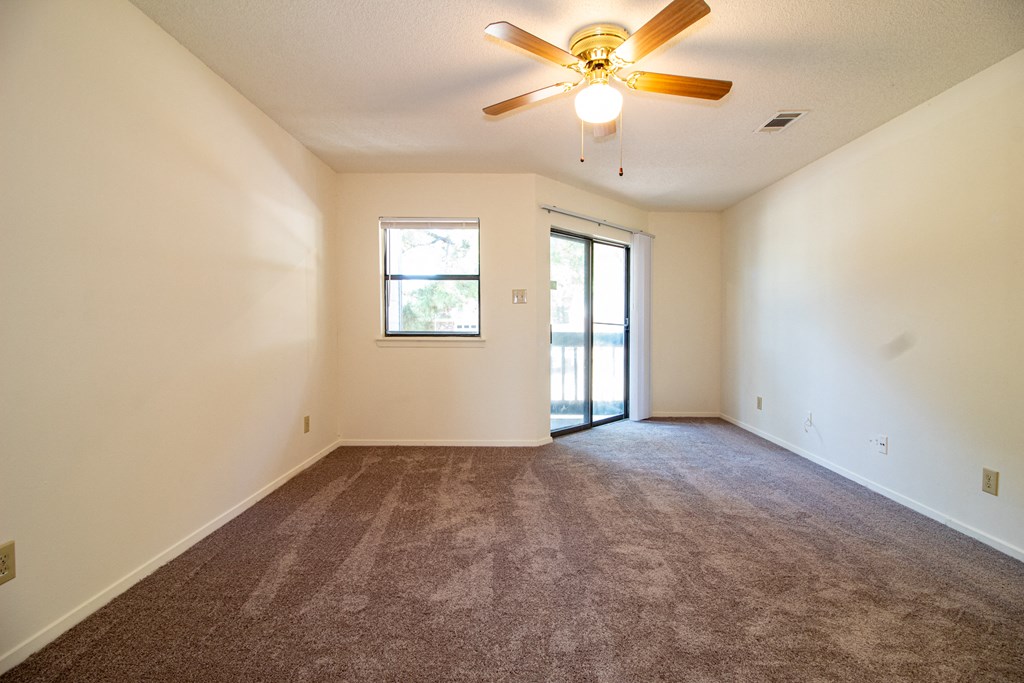 an empty living room with carpet and a ceiling fan