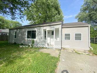 a small gray house with a sidewalk and grass