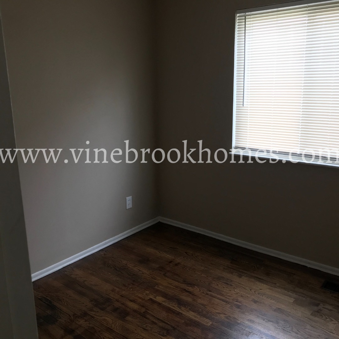 a small room with a wood floor and a window