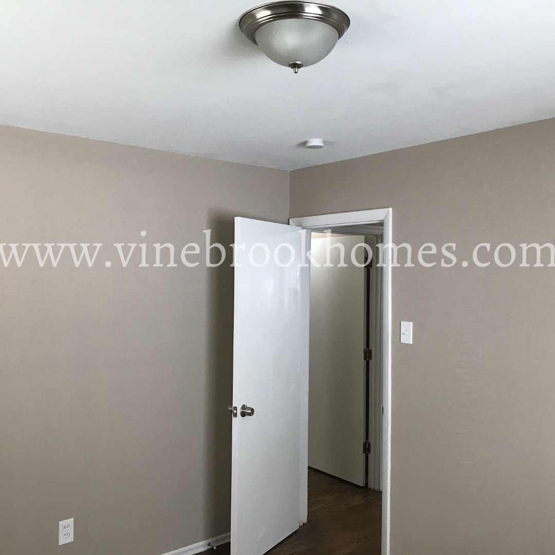 a white door is open to a hallway with a white ceiling fan and a door