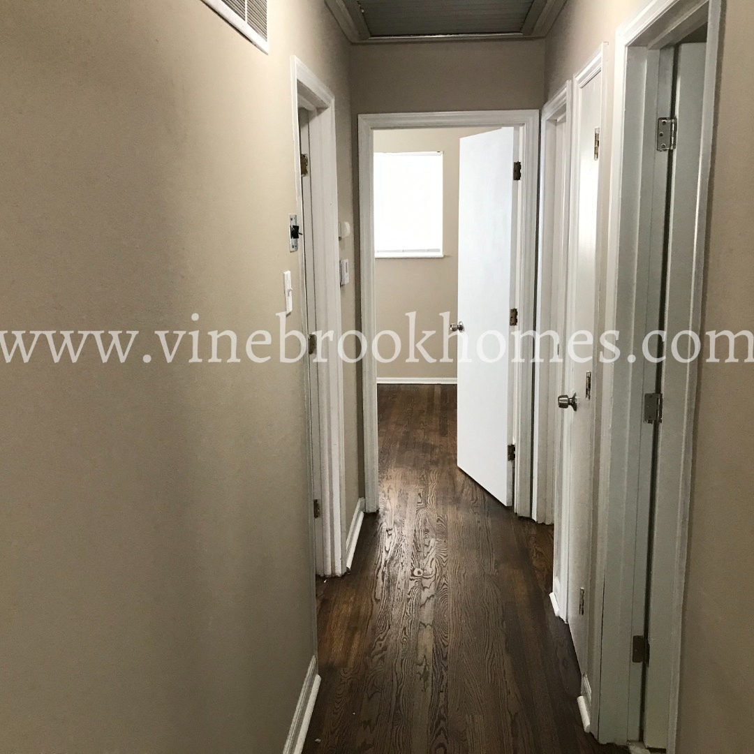 a narrow hallway with a door to a closet and a window