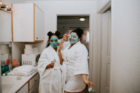 two women with blue makeup on their faces in a kitchen
