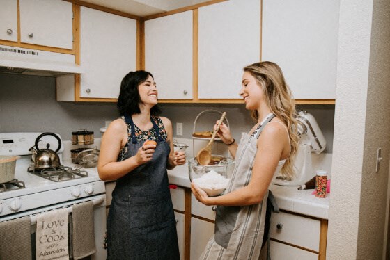 two women standing in a kitchen preparing food
