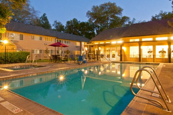 the pool is lit up at night in front of a hotel