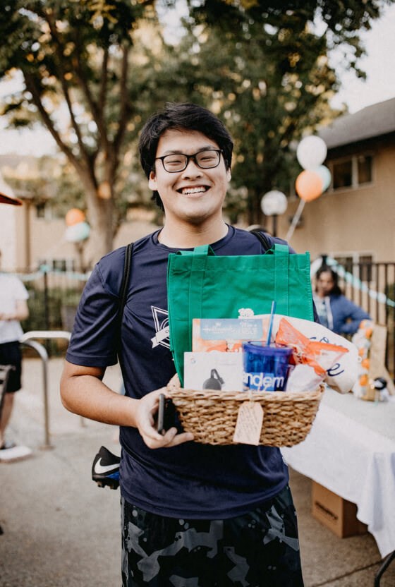 a young man holding a basket of food and drinks